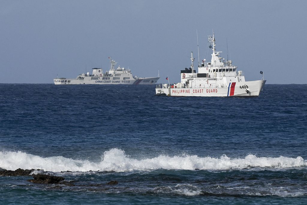 Kapal penjaga pantai China (kiri) dan kapal penjaga pantai Filipina terlihat di dekat Pulau Thitu di Laut China Selatan yang disengketakan, Jumat (1/12/2023).  