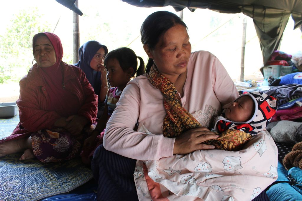 Seorang ibu mengawasi bayinya yang tertidur di tenda pengungsian di RW 003 Desa Cihawuk, Kecamatan Kertasari, Kabupaten Bandung, Jawa Barat, Kamis (19/9/2024). Tenda ini diisi oleh lebih dari 60 jiwa dan sebagian besar berusia anak-anak.