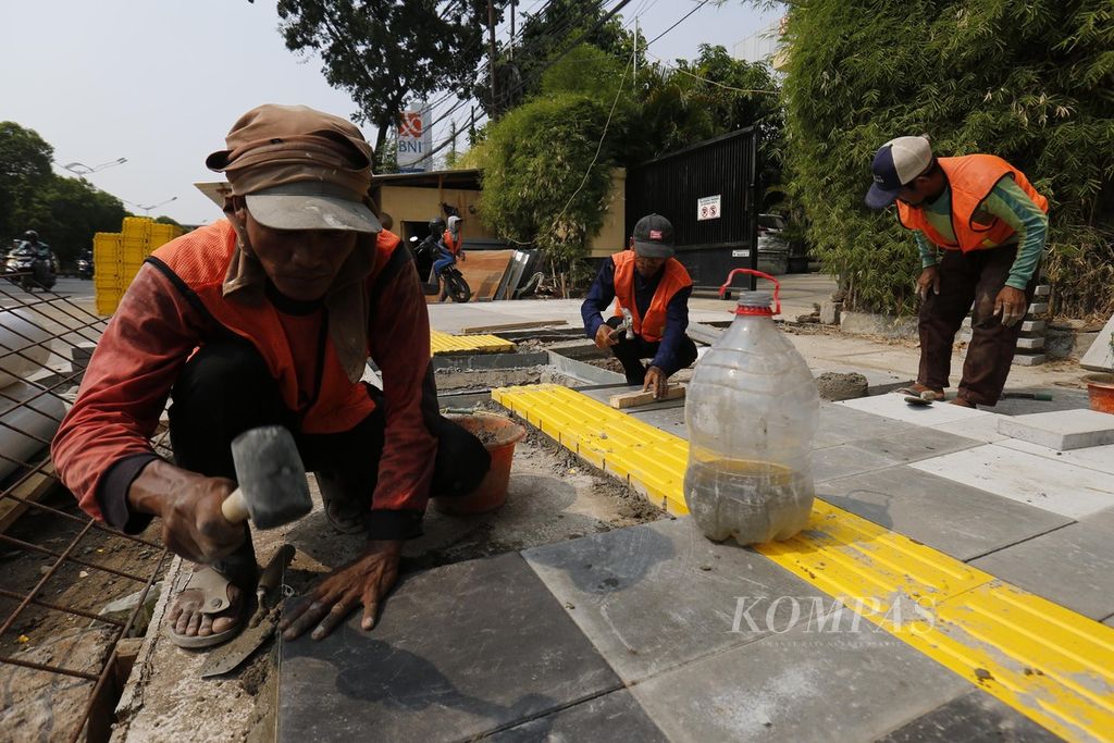 Pekerja menyelesaikan pembangunan trotoar di Jalan Matraman, Jakarta Timur, Rabu (1/11/2023).  