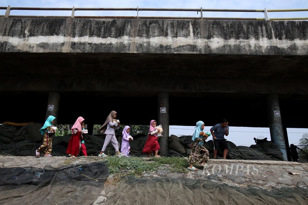 Anak-anak nelayan dan pekerja malam pulang seusai mengikuti kegiatan belajar dan bermain yang diadakan oleh Rumah Belajar Merah Putih bekerja sama dengan sukarelawan Gempita di kolong jembatan Cilincing, Jakarta Utara, Minggu (26/5/2024).