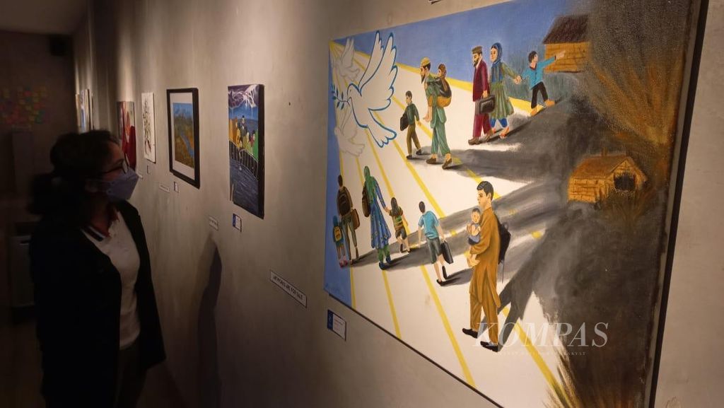 Nabita Maria, seorang pengunjung, tengah mengamati lukisan karya pengungsi-pengungsi Afghanistan di Indonesia. Lukisan-lukisan itu dipamerkan di sebuah kafe di bilangan Fatmawati, Jakarta pada Sabtu (20/8/2022).