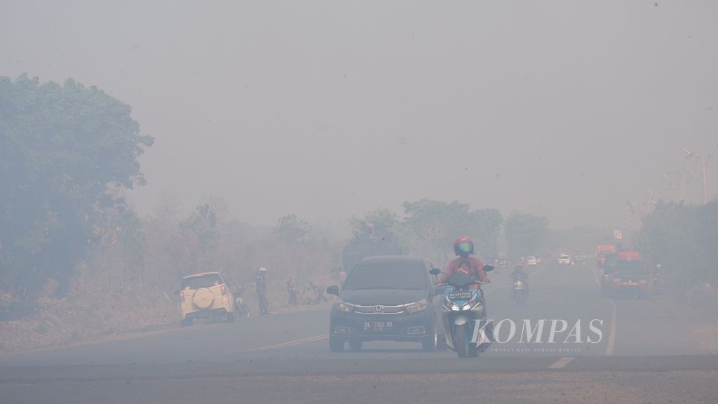 Warga menembus asap pekat akibat kebakaran lahan gambut di Jalan Lingkar Utara, Kelurahan Syamsudin Noor, Kecamatan Landasan Ulin, Kota Banjarbaru, Kalimantan Selatan, Sabtu (7/10/2023). 
