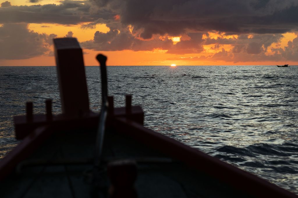Perahu kayu Rustam (48) bergerak pulang saat matahari terbenam setelah menangkap ikan tongkol di perairan yang berjarak sekitar 45 kilometer di sebelah timur Pulau Natuna Besar, Kepulauan Riau, Sabtu (26/3/2022).