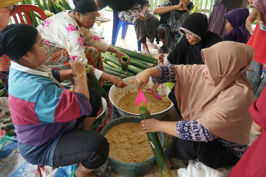 Warga mengisikan adonan lamang (lemang) ubi ke dalam tabung/batang bambu dalam acara "Malamang Sakampuang" di Kelurahan Aie Pacah, Kecamatan Koto Tangah, Kota Padang, Sumatera Barat, Sabtu (31/12/2022). 