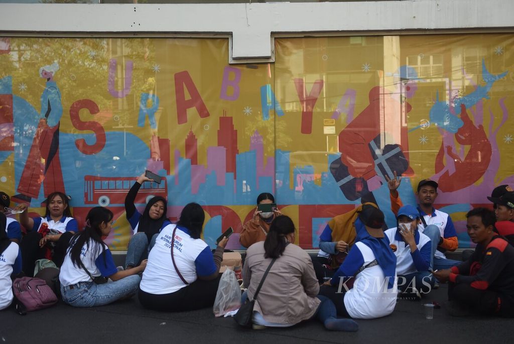 Buruh menunggu rekannya untuk bersama-sama menuju Kantor Gubernur Jawa Timur guna memperingati Hari Buruh, di Surabaya, Rabu (1/5/2024). Ribuan buruh yang berpartisipasi banyak yang datang dari luar kota.