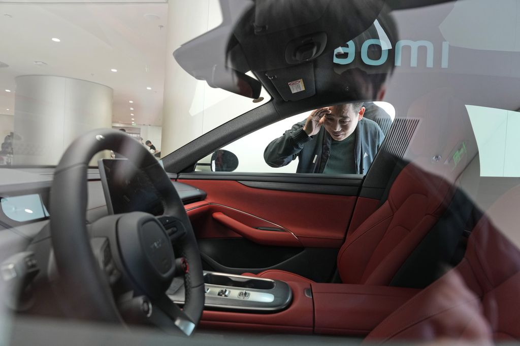 Seorang laki-laki mengintip interior mobil listrik Xiaomi SU7 yang dipamerkan di Beijing, China, Selasa (26/3/2024)