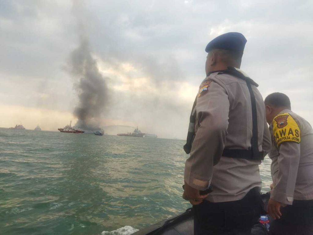 Polisi berada di sekitar lokasi kebakaran Kapal Motor Kirana 1 di perairan sekitar Pelabuhan Tanjung Emas Semarang, Minggu (11/8/2024). 