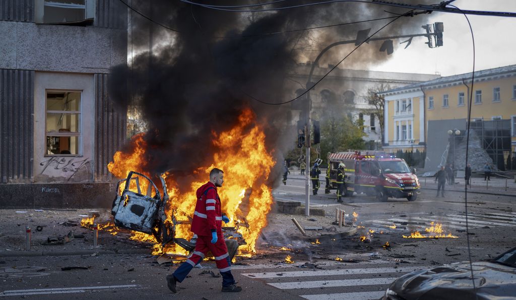 Petugas kesehatan melewati sebuah kendaraan yang terbakar karena terkena rudal Rusia di salah satu sudut kota Kyiv, Ukraina, Senin (10/10/2022). 