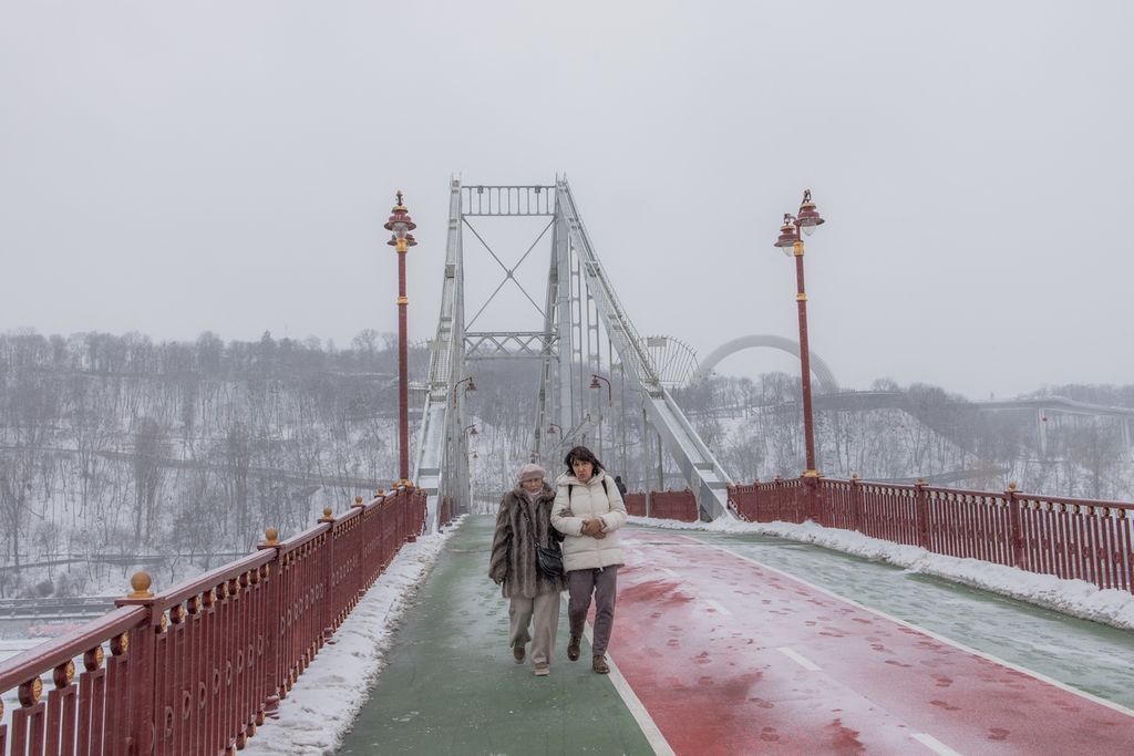 Warga berjalan di jembatan yang melintang di atas Sungai Dnipro, Kyiv, 14 Januari 2024 di tengah invasi Rusia ke Ukraina. 