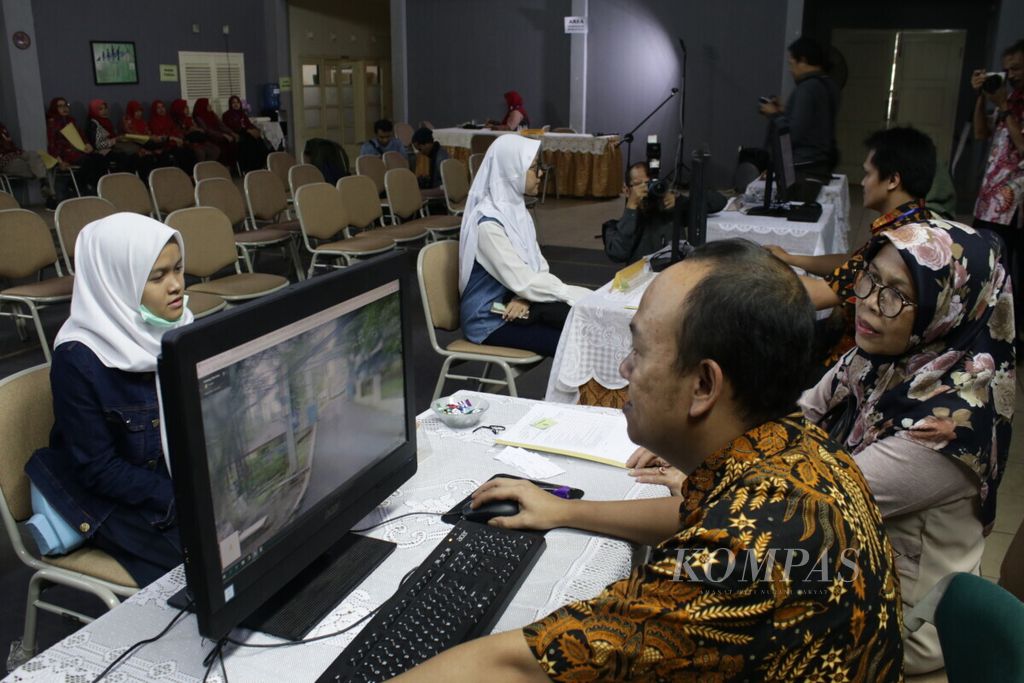 Petugas membantu orangtua calon siswa untuk mengetahui informasi jarak antara sekolah dan rumah dalam uji coba sistem PPDB di SMAN 2 Bandung, Kamis (13/6/2019).