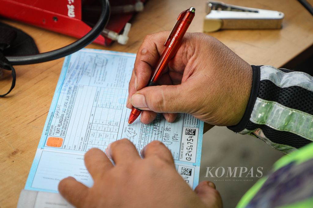 Polisi menulis surat bukti pelanggaran untuk pengendara sepeda motor yang kendaraannya tidak lulus uji emisi di Jalan Perintis Kemerdekaan, Jakarta Timur, Rabu (1/11/2023). 