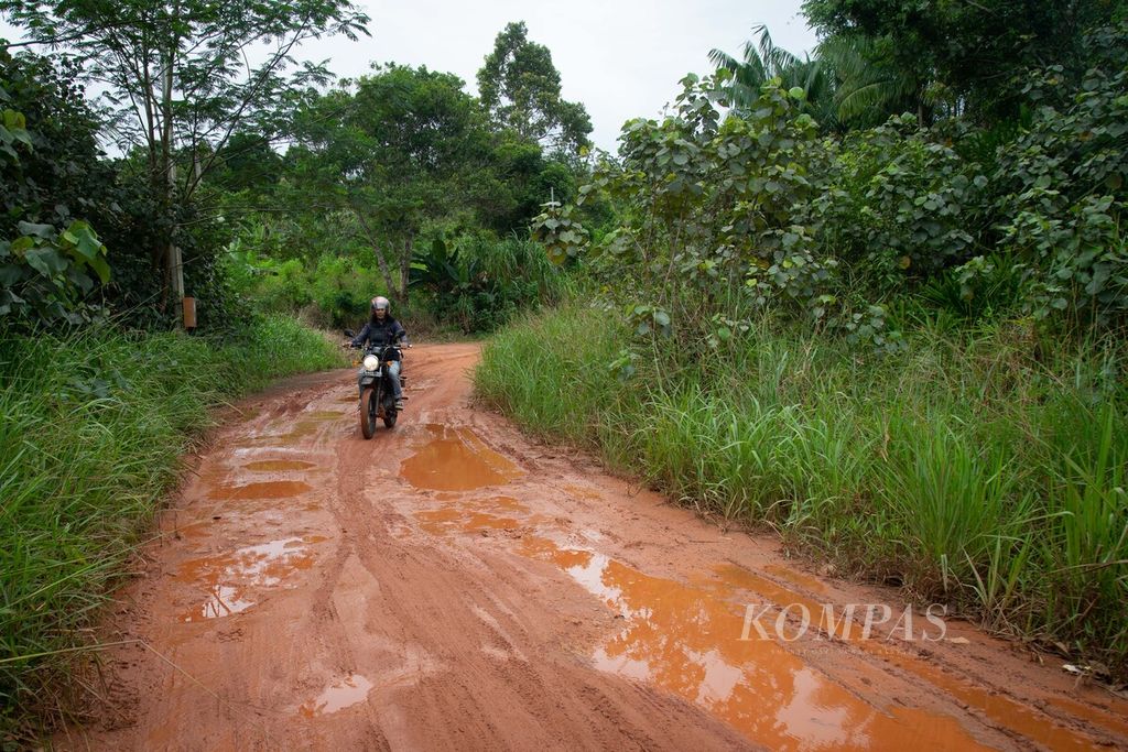 Seorang pengendara sepeda motor melewati jalan tanah berlumpur untuk menuju Kampung Sungai Sadap, Kelurahan Rempang Cate, Kecamatan Galang, Kota Batam, Kepulauan Riau, Jumat (5/8/2022).
