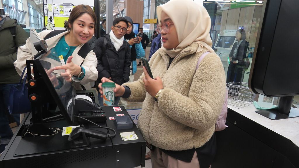 Nanami Terada (kiri) dari Marketing Headquarters Shinagawa Community Development Division, JR East, memandu jurnalis yang menjajal pembayaran mandiri di minimarket di Stasiun Takanawa Gateway, Tokyo, Rabu (15/11/2023). 