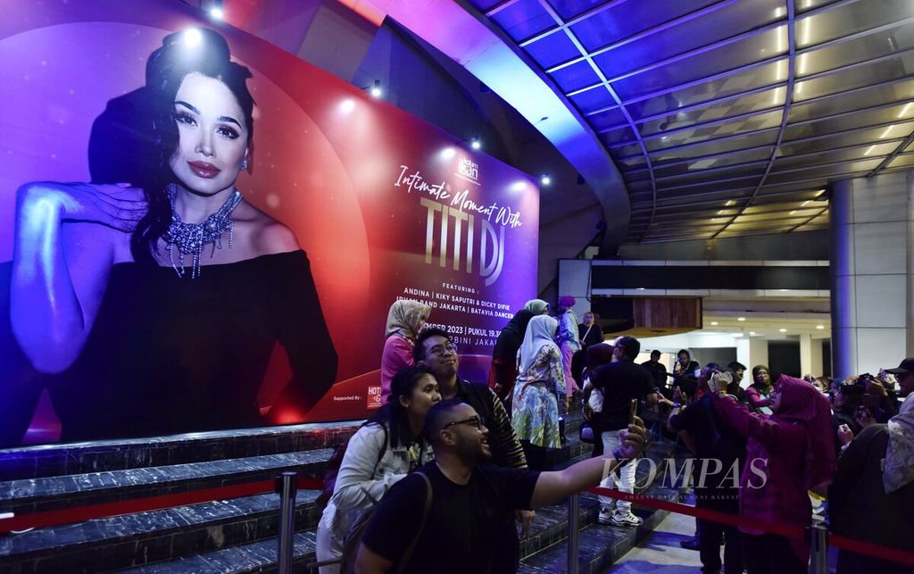 Penonton berfoto di depan pintu masuk lokasi konser Titi DJ bertajuk Intimate Moment with Titi DJ di Balai Sarbini, Jakarta, Jumat (15/9/2023). 