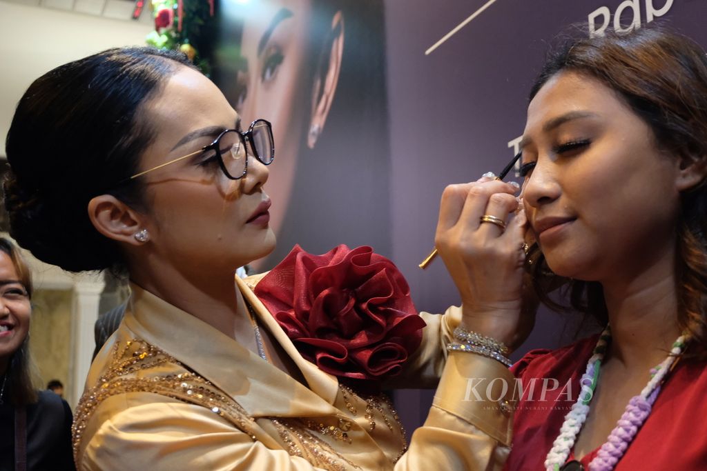 Penyanyi Kris Dayanti (kiri) merias dan memasang bulu mata palsu pada seorang model, Rabu (24/4/2024), di Jakarta, pada peluncuran produk bulu mata palsu kolaborasi Kris Dayanti dengan produsen Lavie Beauty.