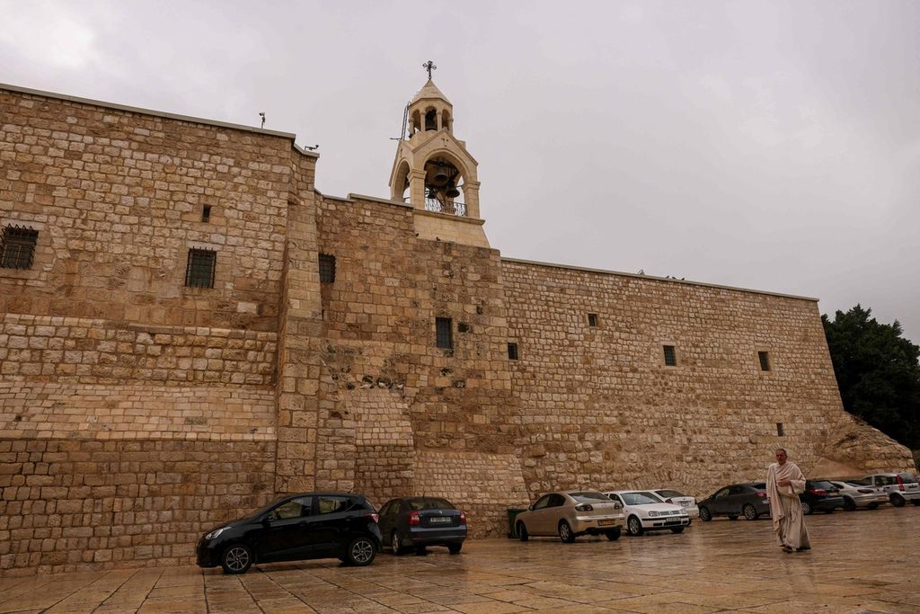 Seorang peziarah berjalan di luar Gereja Kelahiran di kota Bethlehem, Tepi Barat, pada 13 Desember 2023, dua pekan sebelum Natal, di tengah berkecamuknya perang antara Hamas dan Israel di Gaza. 