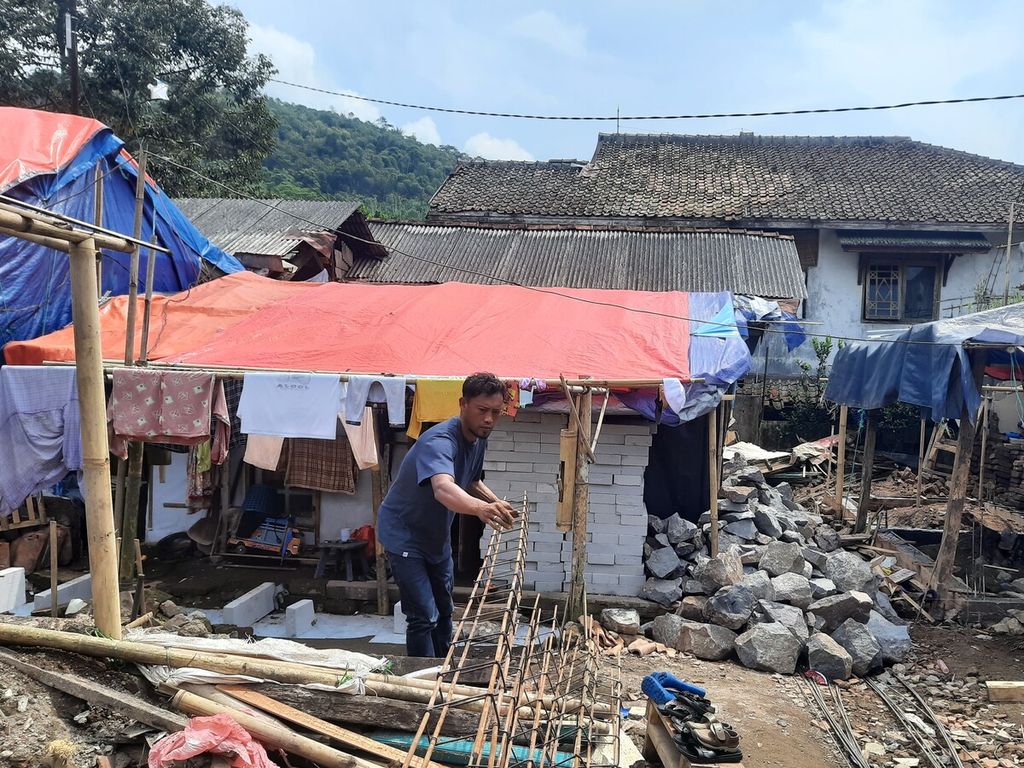 Deni (33), salah satu korban gempa Cianjur, sedang membangun rumah bagi kerabatnya dengan dana bantuan pemerintah di Kampung Gunung Lanjung, Cijedil, Kabupaten Cianjur, Jumat (21/4/2023).