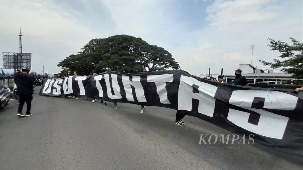 Sebuah spanduk besar bertuliskan Usut Tuntas dibentangkan oleh kelompok suporter Arema FC, Aremania, saat menggelar aksi di atas Flyover Arjosari di Kota Malang, Jawa Timur, Minggu (20/11/2022). 