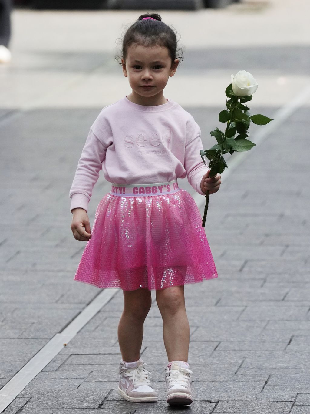 Seorang anak kecil membawa bunga untuk diletakkan di dekat tempat kejadian di Bondi Junction di Sydney, Australia, Minggu (14/4/2024). 