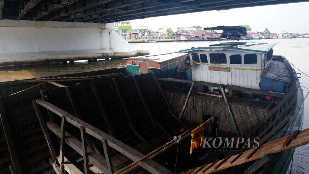 Petugas memasang garis polisi pada KM Abdurrahman 11 di Sungai Martapura, Kota Banjarmasin, Kalimantan Selatan, Jumat (18/3/2022). Kapal motor tersebut ditahan karena mengangkut kayu olahan ilegal. 