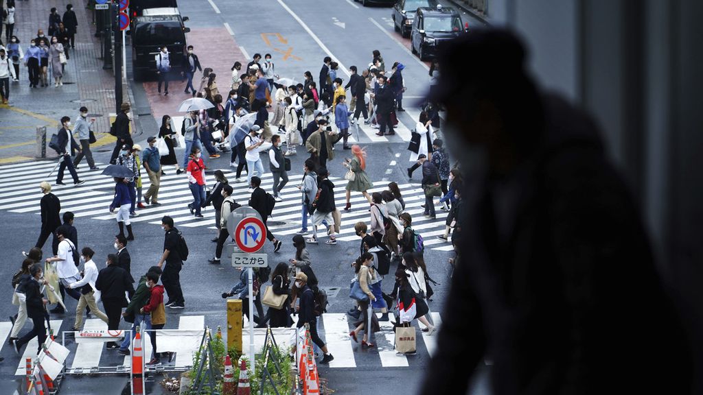 Seorang pria melihat lalu lalang pejalan kaki yang menyeberang jalan di Distrik Shibuya, Jepang, di awal liburan Golden Week atau Minggu Emas, Kamis (29/4/2021). 