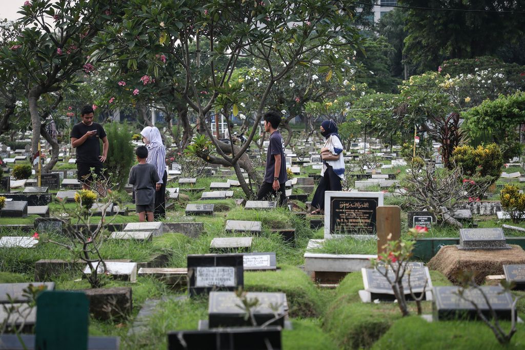 Peziarah melintasi deretan makam di TPU Karet Bivak, Jakarta, Minggu (28/5/2023).
