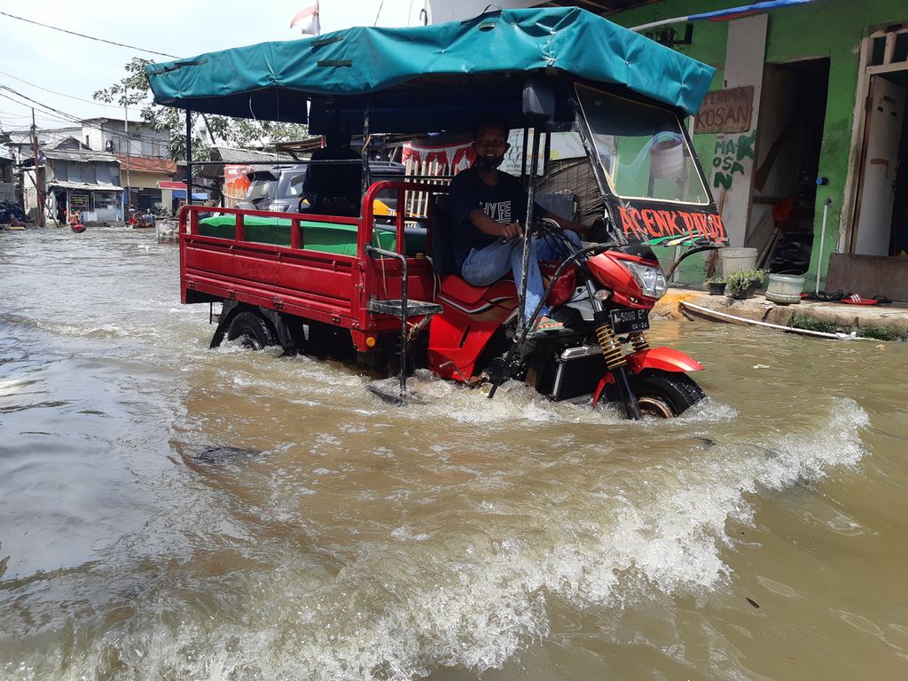 Warga menerjang banjir yang merendam permukiman warga menggunakan kendaraan bermotor di Jalan Dermaga Ujung, Kali Adem, Muara Angke, Jakarta Utara, Selasa (20/10/2020).