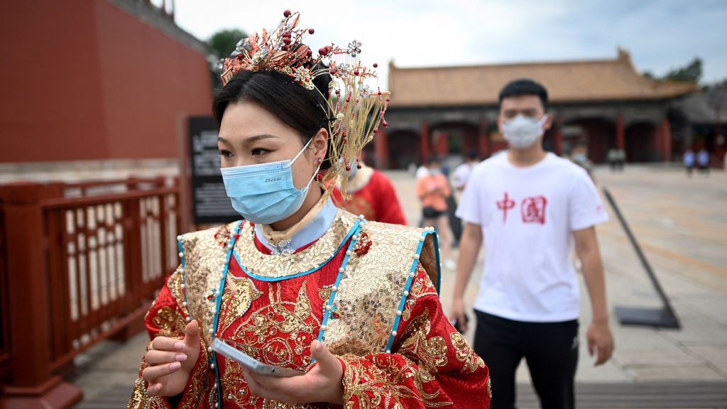 Perempuan dengan mengenakan masker dan Hanfu, pakaian tradisional China, bersiap masuk ke Kota Terlarang (Forbidden City) di Beijing, China, Selasa (7/6/2022). Pemerintah China mulai melonggarkan beberapa pembatasan terkait Covid-19. Museum menjadi salah satu tempat yang sudah bisa dikunjungi. 