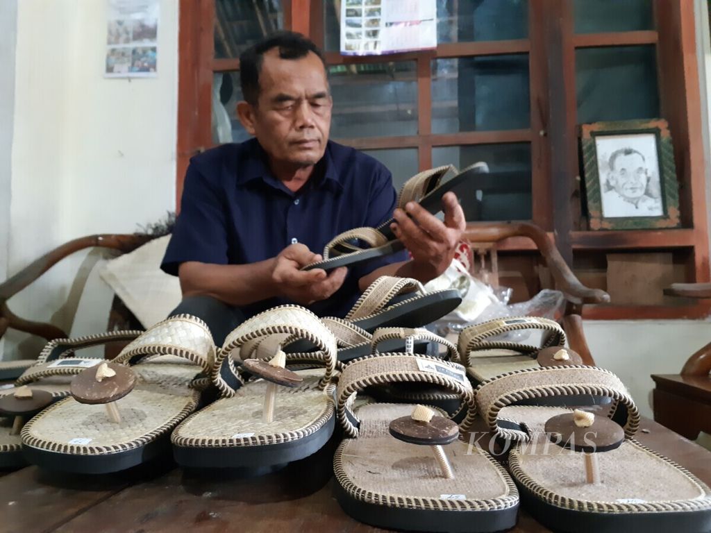 Pemilik usaha kerajinan BW Craft Borobudur, Basiyo, menata sandal-sandal buatannya, Jumat (12/11/2021), di rumahnya yang berlokasi di Desa Borobudur, Kecamatan Borobudur, Kabupaten Magelang, Jawa Tengah. Sandal buatan Basiyo itu merupakan sandal khusus yang bakal diwajibkan dipakai oleh pengunjung yang ingin naik ke Candi Borobudur.