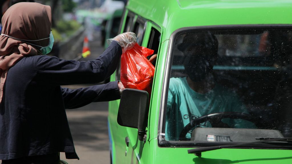 Sukarelawan membagikan bahan makanan pokok kepada sejumlah sopir angkutan kota yang melintas di Jalan Juanda, Kota Bogor, Jawa Barat, Senin (13/4/2020). 