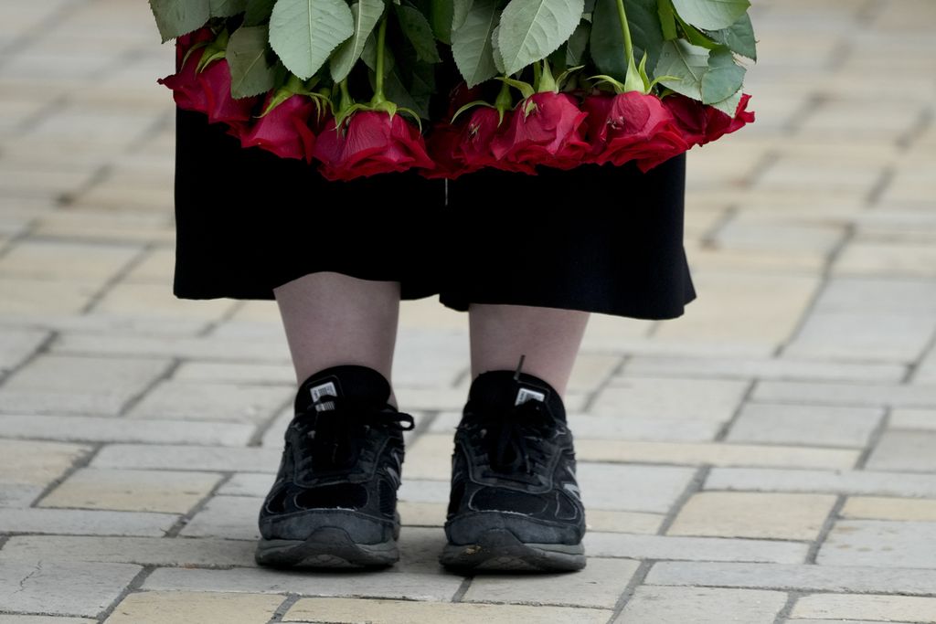 Seorang perempuan memegang bunga mawar saat pemakaman tentara di Kyiv, Ukraina, 18 Juni 2022. 