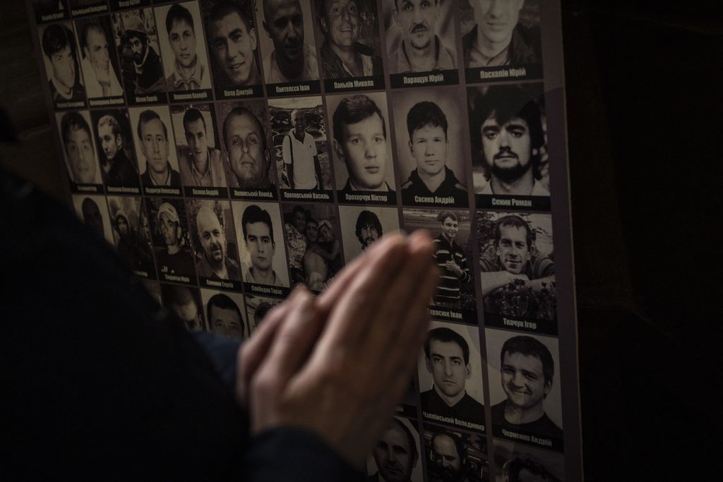 Seorang jemaat tengah berdoa di depan gambar sejumlah prajurit Ukraina yang tewas pada tahun 2014 di Gereja St Peter dan Paul Garrison di Lviv, Ukraina barat, MInggu (6/3/2022). 