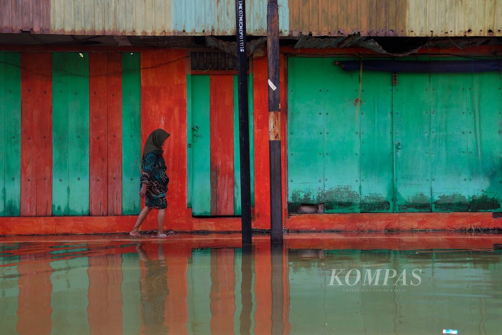 Warga melintasi kawasan pertokoan yang terpaksa tutup dalam beberapa hari ini setelah banjir melanda kawasan alun-alun Kabupaten Demak, Jawa Tengah, Rabu (20/3/2024).