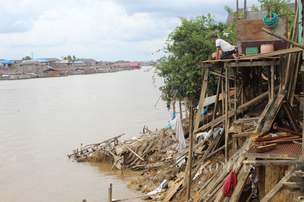 Pemilik rumah yang terdampak abrasi memperhatikan tanah yang terus terkikis air sungai di Gang Sepakat, Kelurahan Pahandut, Kota Palangkaraya, Kalimantan Tengah, Minggu (8/1/2023). 
