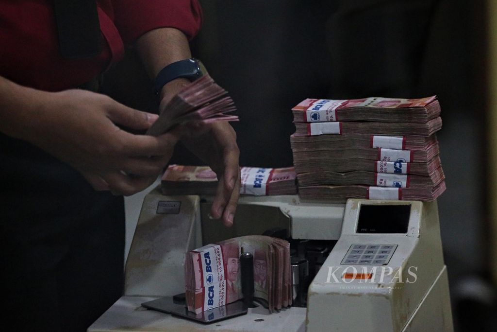 Petugas menghitung uang rupiah di tempat penukaran valuta asing Dolarindo di kawasan Melawai, Jakarta Selatan, Senin (6/12/2021). 