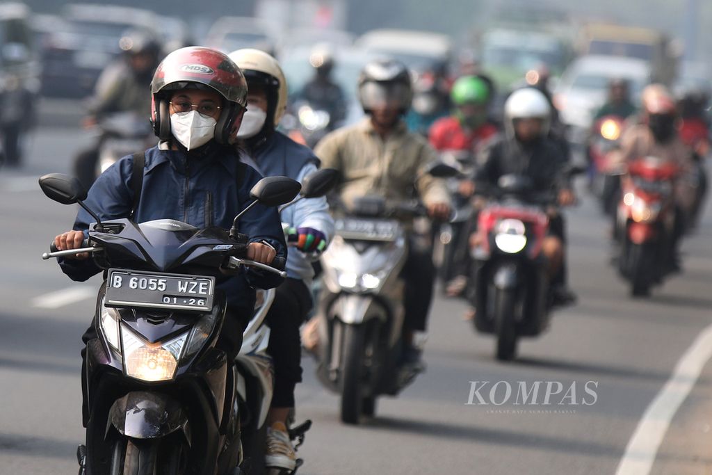 Pengendara sepeda motor mengenakan masker saat melaju di Jalan Serpong Raya, Tangerang Selatan, Banten, Jumat (11/8/2023). 