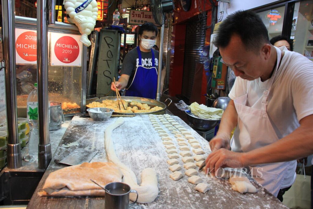 Pedagang ”Pa Tong Go Savoey” menyiapkan adonan <i>patongo </i>atau cakwe di kawasan Chinatown, Bangkok, Thailand, Rabu (7/8/2019). Jajanan kaki lima itu telah direkomendasikan buku peringkat hotel dan restoran Michelin Guide.