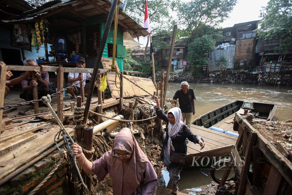 Warga menggunakan eretan untuk menyeberang di Kali Ciliwung, Kawasan Jatinegara, Jakarta, Senin (5/8/2024). Pemerintah DKI Jakarta menargetkan pada tahun 2027 penataan RW kumuh dapat terselesaikan.