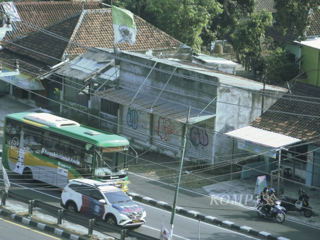 Bus Trans Jogja melintasi bendera pendukung PS Sleman di Jalan Ring Road Utara, Depok, Kabupaten Sleman, Daerah Istimewa Yogyakarta, Selasa (9/8/2022). Di beberapa sisi jalan, bendera masih tetap berkibar meski kondisinya sudah tidak baik.