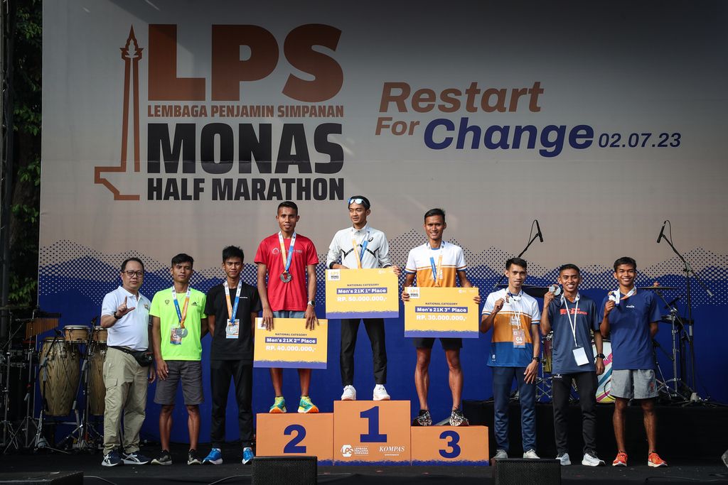 Peraih emas kategori nasional pria, Robi Syianturi (tengah), peraih perak kategori nasional pria, Rikki (keempat dari kiri), dan peraih perunggu kategori nasional pria, Pandu Sukarya (keempat dari kanan), berfoto bersama Pemimpin Redaksi Harian <i>Kompas</i> Sutta Dharmasaputra (kiri) seusai penyerahan hadiah dan medali dalam ajang LPS Monas Half Marathon di Istora Senayan, Jakarta, Minggu (2/7/2023). 