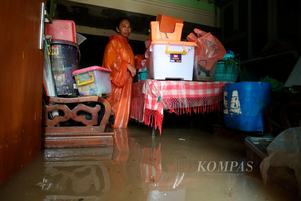 Salah satu warga berusaha menyelamatkan harta bendanya di atas meja agar tidak terendam banjir yang melanda Kampung Sawah Besar, Kota Semarang, Jawa Tengah, Kamis (14/3/2024).