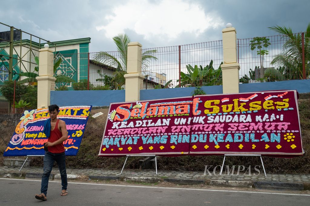 Perajin bunga, Payung (31), melintas di depan papan bunga berisi harapan untuk mendapat keadilan yang dipasang di Pengadilan Negeri Batam, Kepulauan Riau, Senin (6/11/2023).