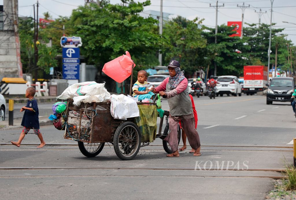Satu keluarga berjalan beriringan dengan gerobaknya saat mereka memulung sampah yang dapat dijual di Jalan Kaligawe, Kota Semarang, Jawa Tengah, Rabu (22/2/2022). Minimnya akses ekonomi, kesehatan, dan pendidikan menyebabkan kemiskinan terus mengakar pada kelompok warga miskin ekstrem. 