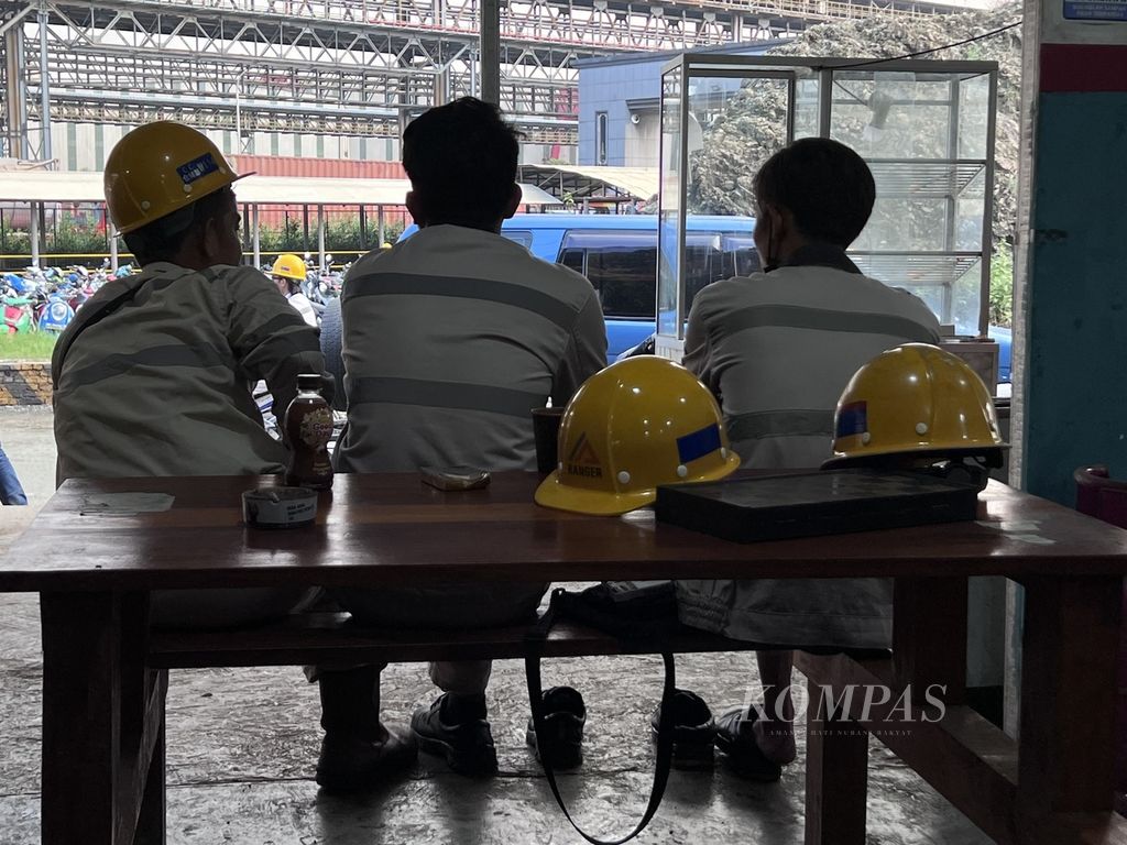 Tiga pekerja PT Indonesia Morowali Industrial Park beristirahat di luar kawasan pabrik di Kecamatan Bahodopi, Morowali, Sulawesi Tengah, sepulang kerja, 29 Desember 2023.