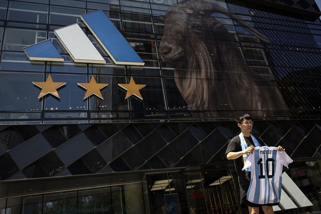 Warga China memegang replika kaus timnas sepak bola Argentina milik Lionel Messi di depan toko Adidas, di Beijing, Selasa (13/6/2023). 