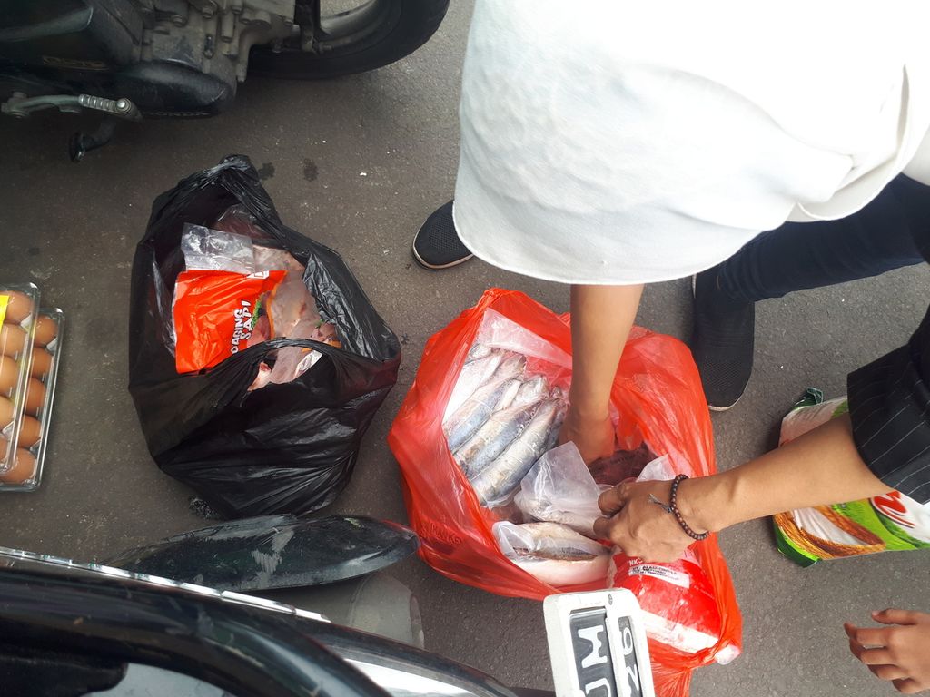 Warga memasukkan bantuan bahan pokok bersubsidi ke dalam keresek di Food Station Tjipinang Raya, Pisangan Timur, Pulo Gadung, Jakarta Timur, Jumat (2/12/2022).