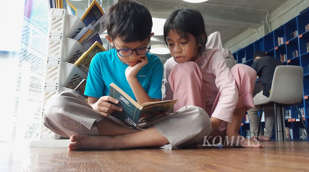 Dua orang anak sedang membaca buku di Perpustakaan Taman Literasi Martha Christina Tiahahu, Kamis (4/4/2024) sore. Membaca buku menjadi salah satu pilihan kegiatan menunggu waktu berbuka puasa atau ngabuburit.