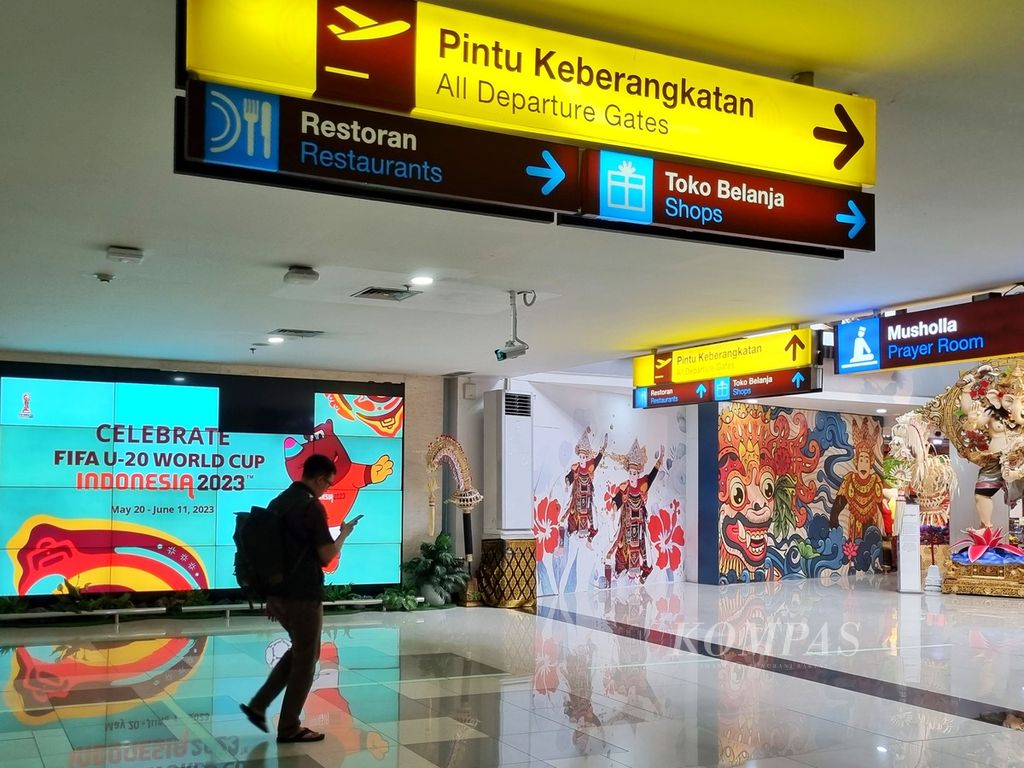Seorang penumpang melintas di video elektronik promosi Piala Dunia U-20 2023 yang masih tayang di terminal keberangkatan Bandara Internasional I Gusti Ngurah Rai, Bali, Selasa (4/4/2023). Bali seharusnya menjadi salah satu dari enam kota tuan rumah turnamen yunior itu yang telah batal berlangsung di Tanah Air.