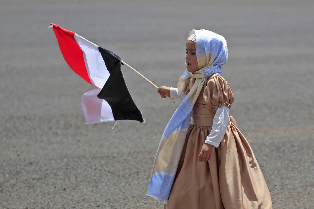 Anak perempuan mengibarkan bendera Yaman di Bandara Sana'a, Yaman, Minggu (16/4/2023), saat menunggu kedatangan anggota milisi Houthi yang baru dibebaskan.