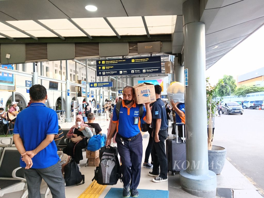 Seorang <i>porter</i> membawa barang penumpang yang baru saja tiba di Stasiun Pasar Senen, Jakarta Pusat, Kamis (9/3/2023), setelah melakukan perjalanan dari luar kota.